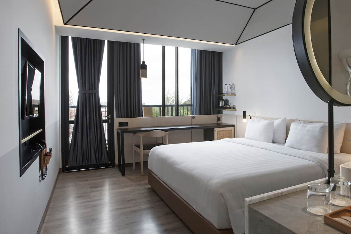 A modern hotel room with a large bed, a desk, and a TV.