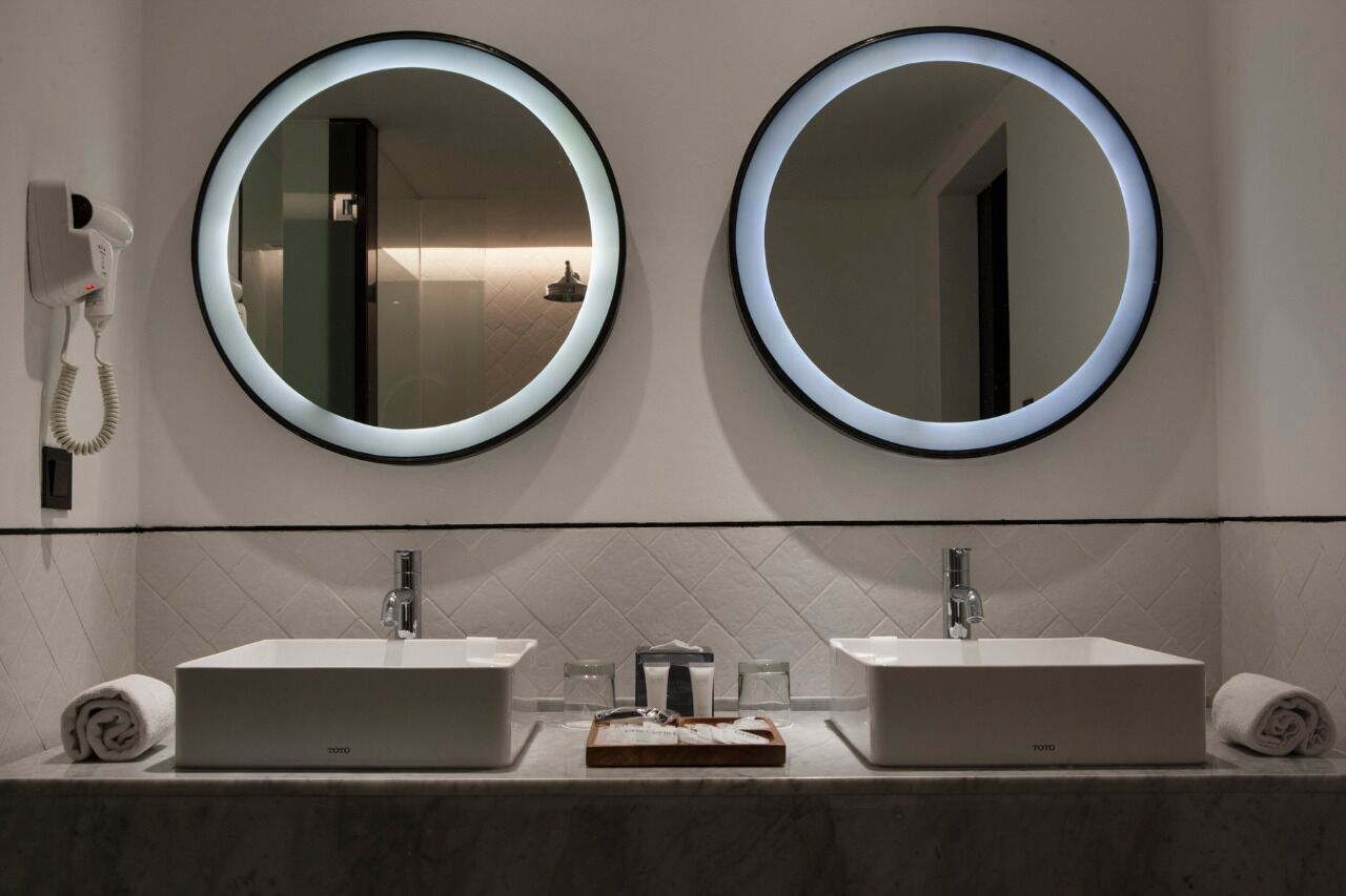 A bathroom with two round mirrors, a hairdryer, and two sinks.