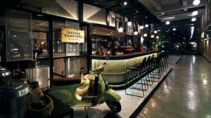 Interior de una cafetería con mostrador, zona de estar y exhibición de equipos de café.