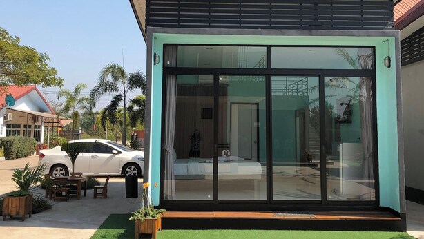 A modern building with large glass windows, a car parked outside, and a small outdoor seating area. - Ban Ton Resort (Udon Thani)