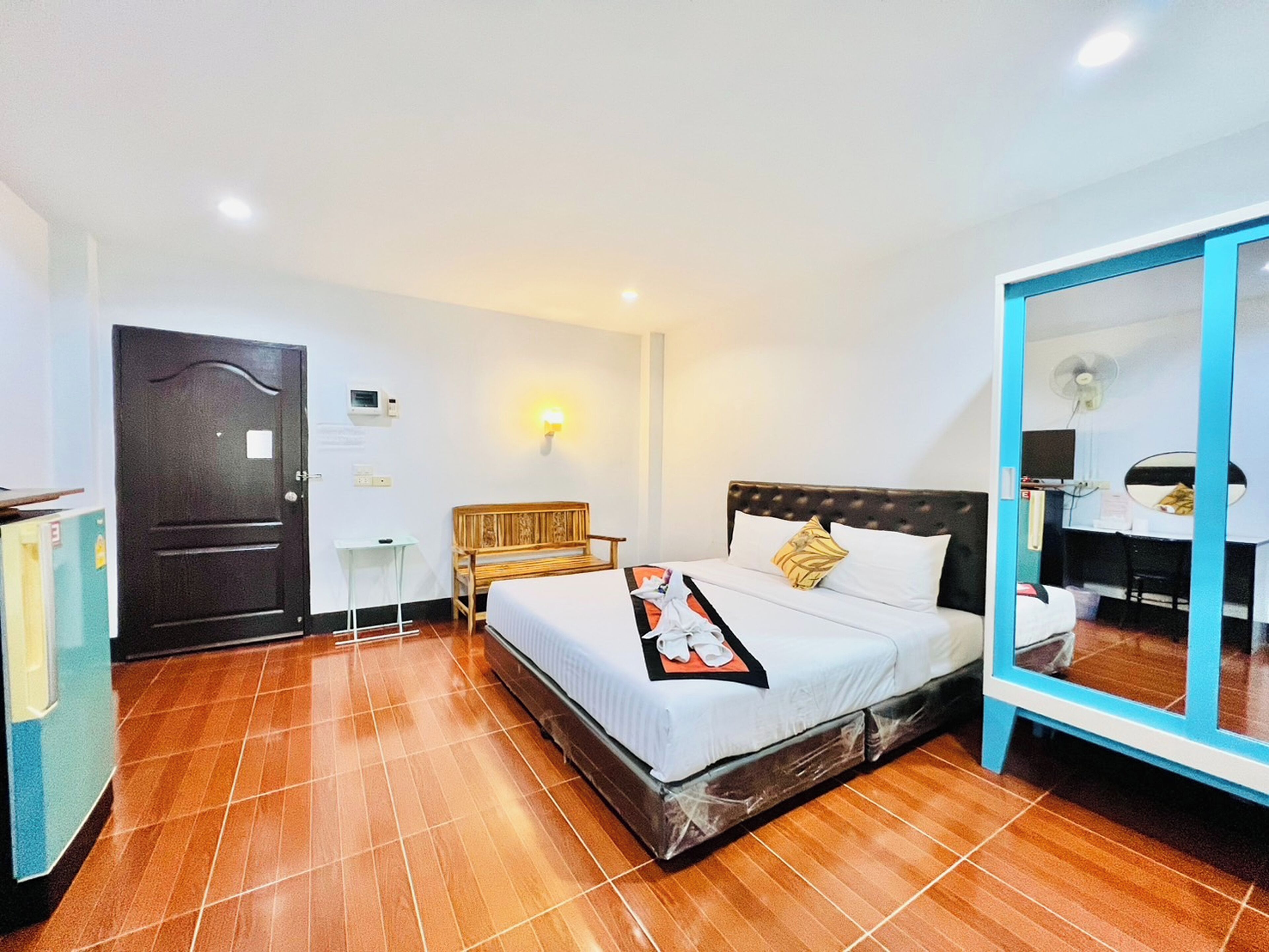 A hotel room with a bed, a bedside table, a mirror, and a wardrobe.