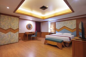 Una habitación de hotel con cama, escritorio, silla y televisor.