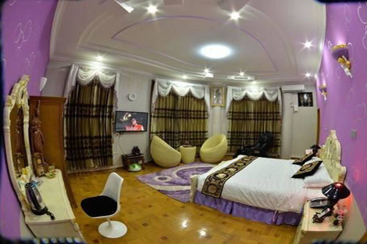 A bedroom with a bed, a chair, a TV, and a desk.