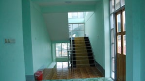 A narrow hallway with a tiled floor, a staircase, and a door leading to an outdoor area. - Hotel Venus (Mandalay)