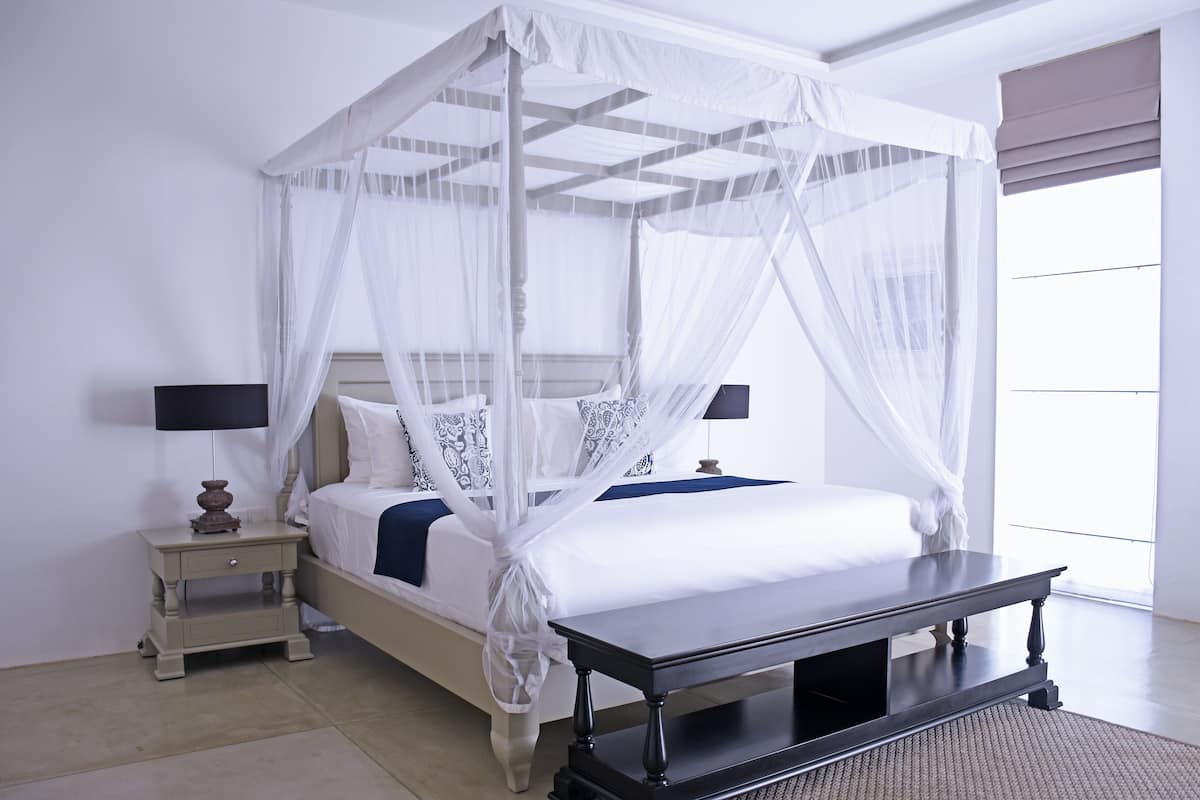 Un lit à baldaquin à quatre poteaux, avec une table de chevet et une table, dans une chambre d’hôtel.