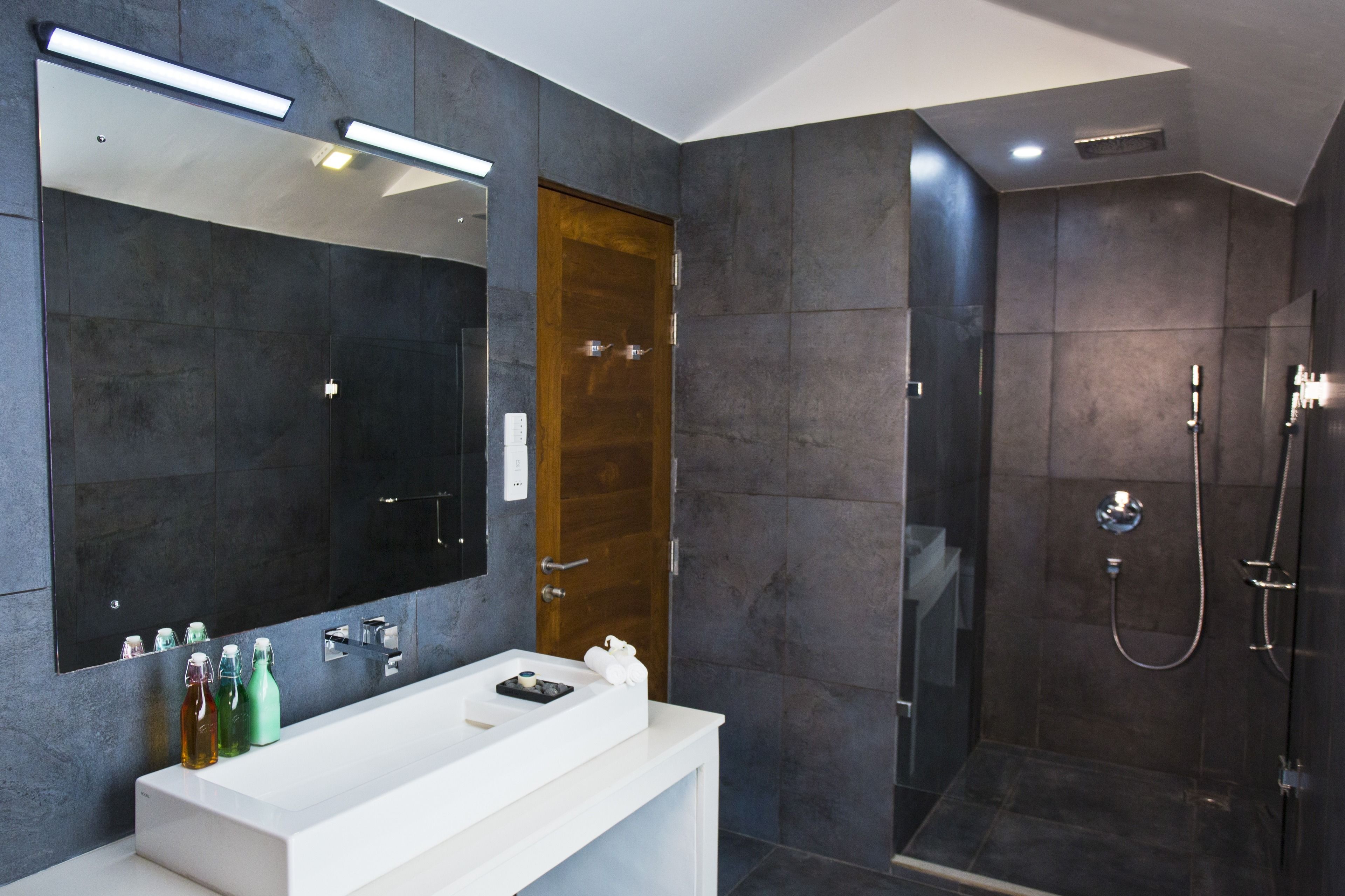A modern bathroom with a large mirror, a white vanity, and a glass-enclosed shower.