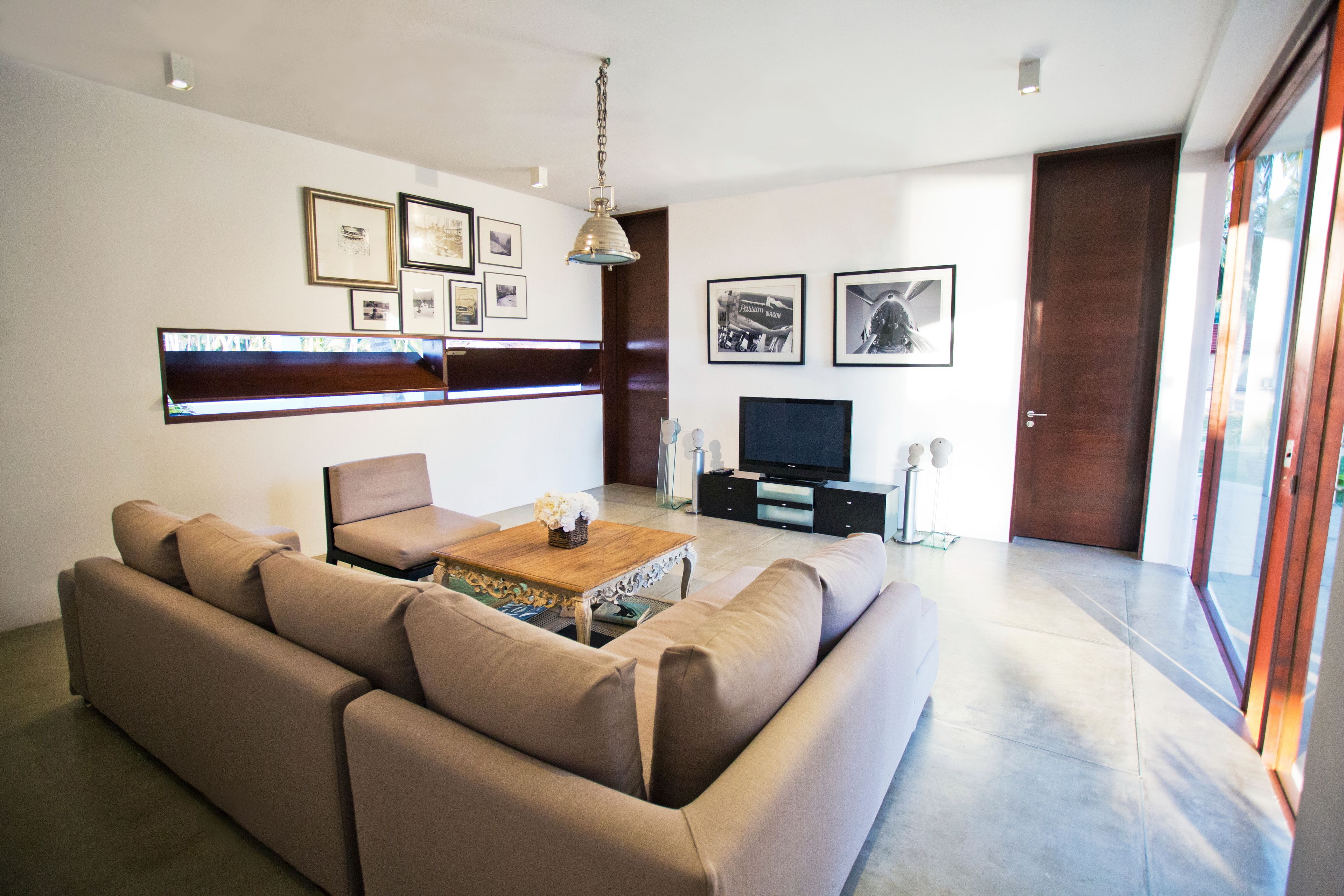 A modern living room with a sofa set, a coffee table, a flat-screen TV, and framed pictures on the wall.