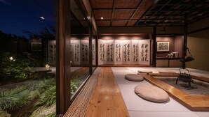 Um interior japonês tradicional com tatames, teto de madeira e caligrafia nas paredes.