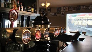 Un bar amb diverses aixetes de cervesa, una barra i una finestra que ofereix vistes d'un edifici a l'exterior.