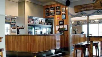 A bar area with wooden paneling, a refrigerated display case, and a wall adorned with framed certificates.