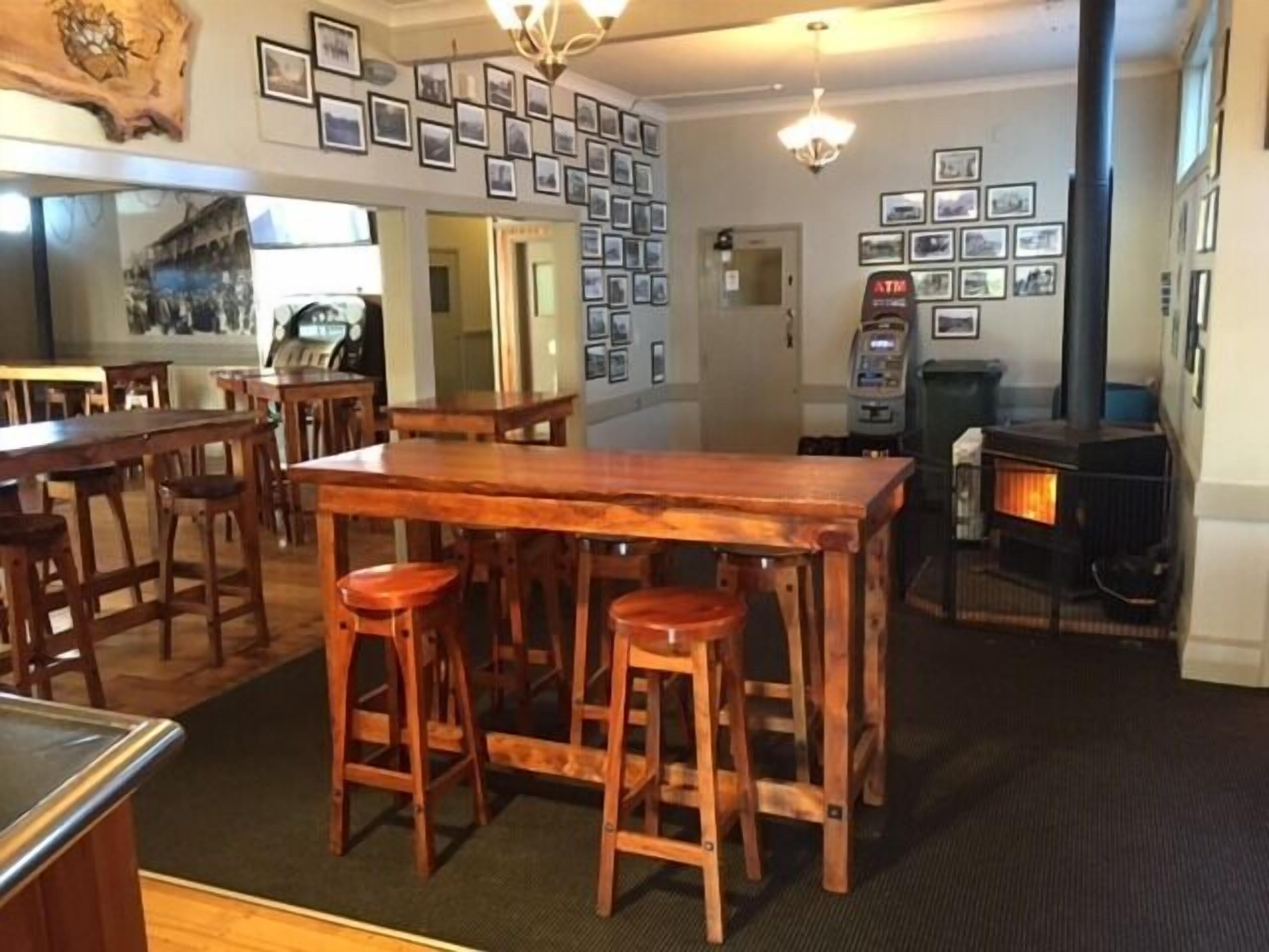A cozy bar area with wooden stools, a large wooden table, and a fireplace.