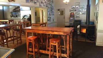 A cozy bar area with wooden stools, a large wooden table, and a fireplace.