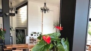 Interior de restaurant amb taules i cadires de fusta, plantes en testos i lluminàries penjants.
