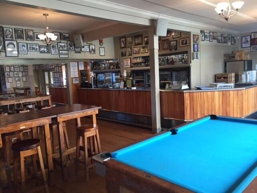A bar area with wooden furniture and a pool table.