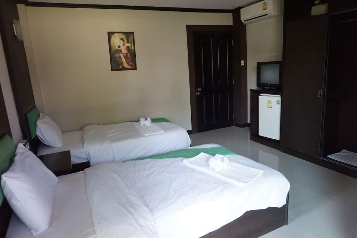 Habitación de hotel con dos camas, un cuadro en la pared, televisor y refrigerador.