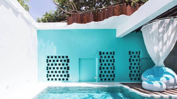 A swimming pool with a blue and white color scheme, surrounded by a white wall with a wooden fence overhead. - Villa Winding Land (Hengchun)