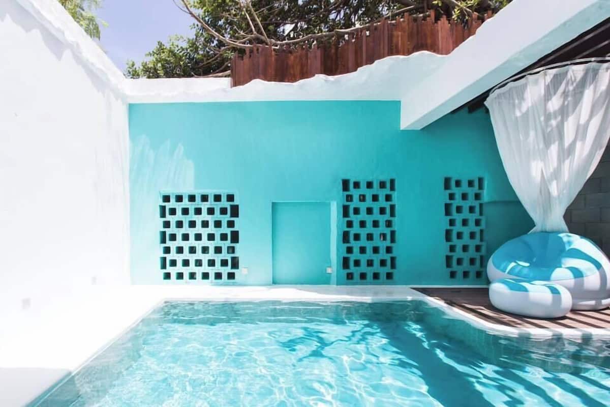 Una piscina con diseño azul y blanco, rodeada por un muro blanco y una cerca de madera en la parte superior.