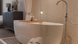 A modern bathroom with a freestanding bathtub, a wooden stool with towels, and a vanity with a mirror and lights. - Villa Winding Land (Hengchun)