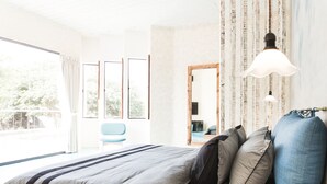 Quarto com cama grande, vista para o exterior e janela com cortinas.