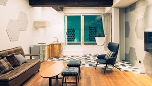 A modern living room with a brown leather sofa, a wooden coffee table, and a blue armchair. - Villa Winding Land (Hengchun)