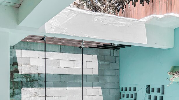 Piscina com piso azulejado e degraus para acesso. Há postes de metal na piscina, e uma parede de tijolos com uma seção de azulejos brancos.
