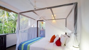 Un dormitorio con cama con dosel, una mesita de noche con lámpara y vistas a la vegetación.