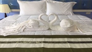 Een bed met witte lakens en twee handdoeken gevouwen in de vorm van zwanen.