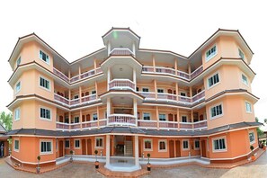 A multi-story building with balconies, a central entrance, and a symmetrical facade.