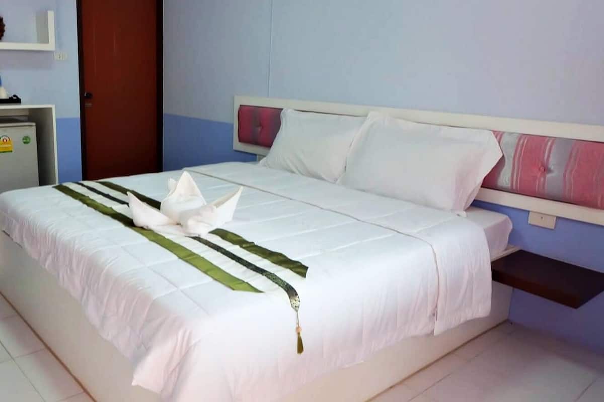 A neatly made bed with white linens and a decorative swan pillow.