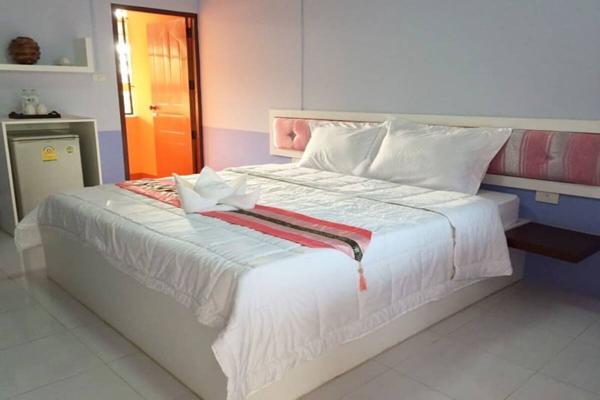 A hotel room with a bed, a desk, and a door.