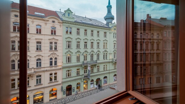 A view of a historic building with multiple stories and ornate architectural details, including a tower with a spire. - Vinohradský dům (Prague)