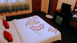 A hotel room with a neatly made bed, a television, and a minibar. - Morning Glory Inn (Kalaw)