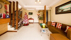 Un saló modern amb una escala, un arbre de Nadal, un sofà amb coixins florals i un quadre a la paret.
