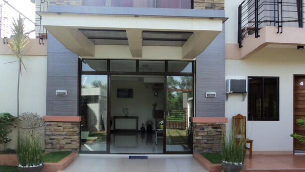 Una casa moderna de dos pisos amb entrada de vidre, detalls de pedra i una petita zona de jardí.
