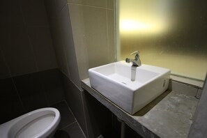Une salle de bain avec un lavabo blanc, un miroir et des toilettes.