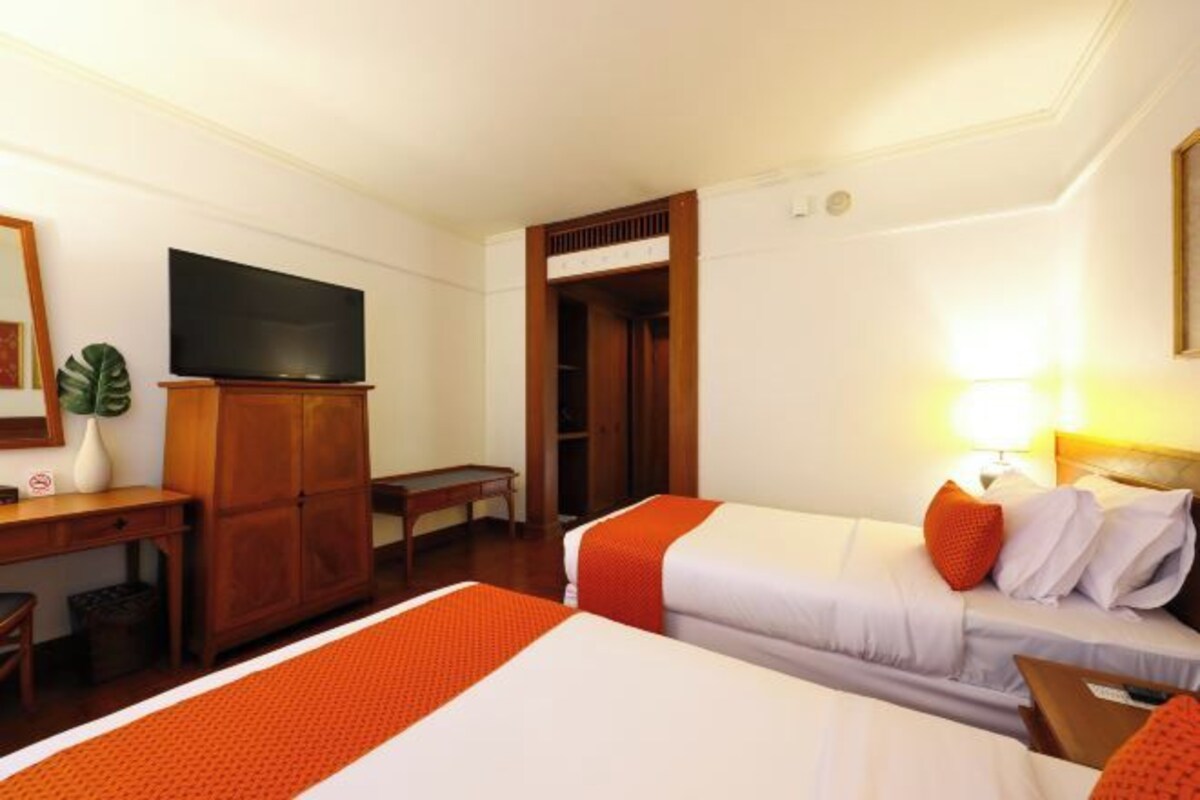 A hotel room with two beds, a TV, a desk, and a wardrobe.