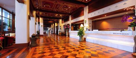 Un vestíbulo de hotel con piso a cuadros, una mesa de registro y un área de recepción.