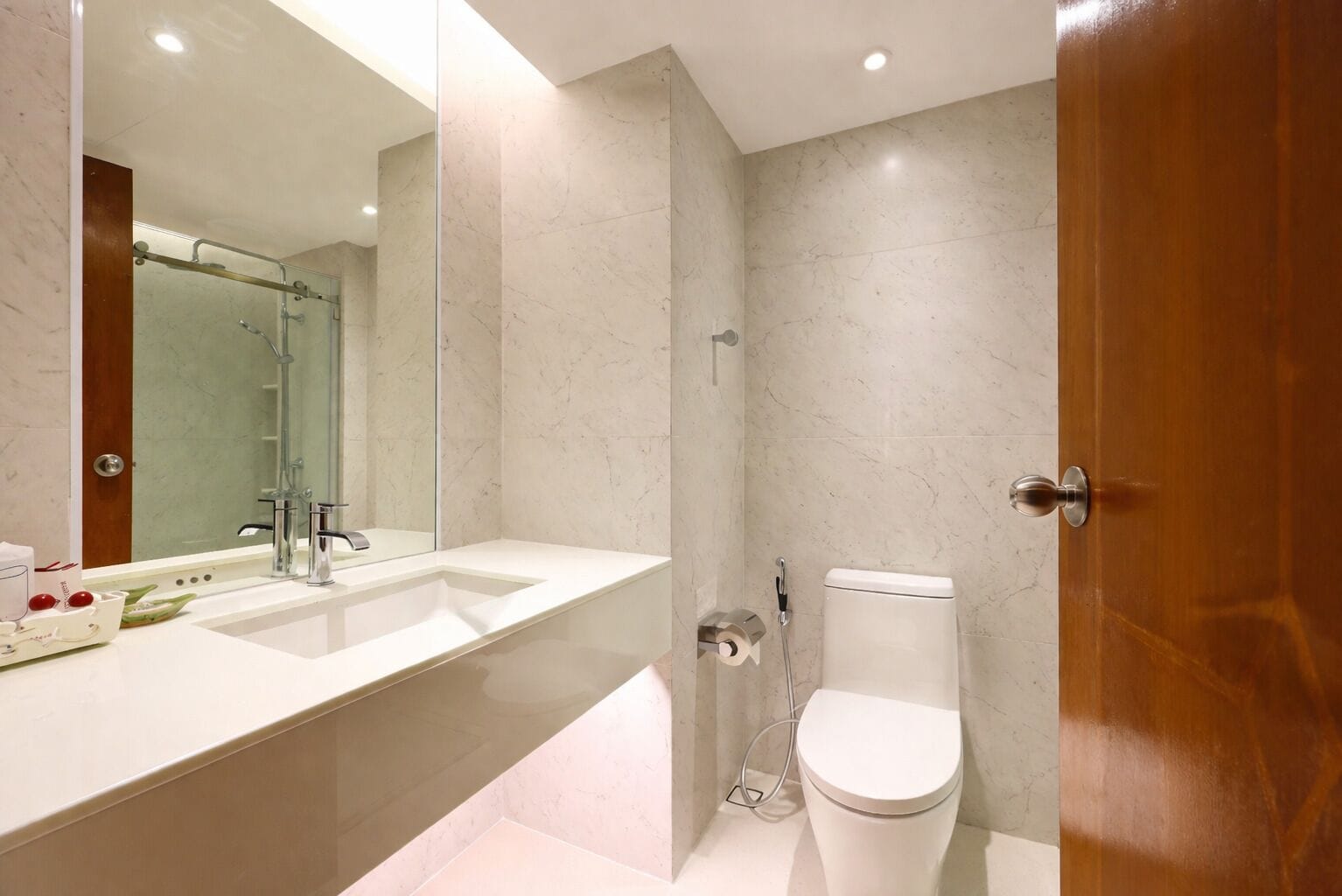 Une salle de bain moderne avec un grand miroir, deux lavabos, des toilettes et une douche.