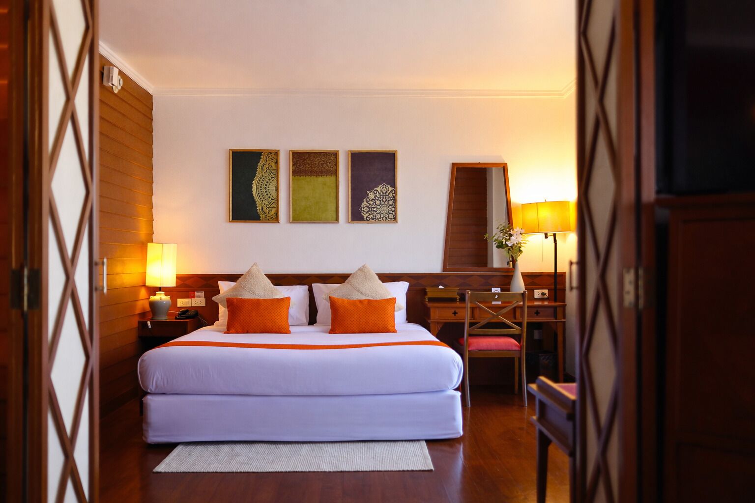 A hotel room with a large bed, two bedside tables, a desk, and a chair.