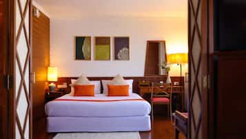 Una habitación de hotel con una cama grande, dos mesitas de noche, un escritorio y una silla.