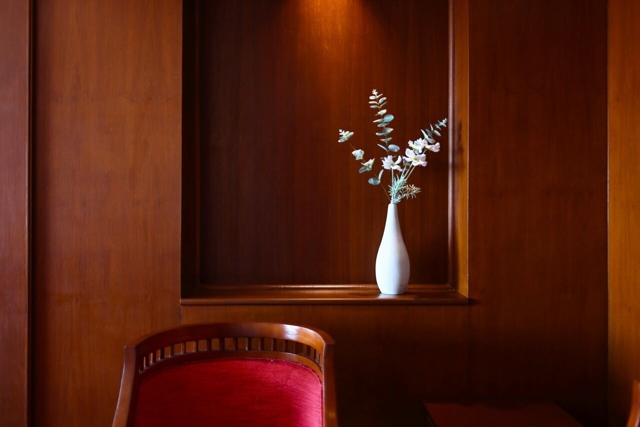 A wooden wall with a white vase containing white flowers.
