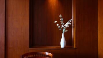 Una pared de madera con un jarrón blanco lleno de flores blancas.