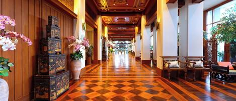 A hotel lobby with a checkered floor, wooden paneling, and traditional decor.