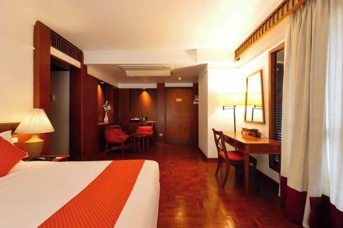 Une chambre d’hôtel avec un lit, un bureau, une chaise et une petite table.