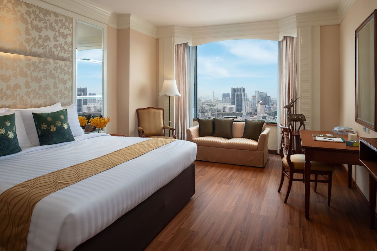 Une chambre d’hôtel avec un grand lit, un canapé, un bureau et une vue sur la ville.