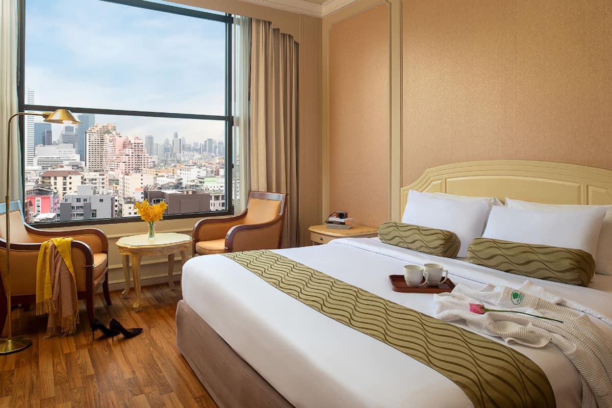 Une chambre d’hôtel avec un grand lit, un bureau avec une chaise, une petite table et une vue sur la ville.