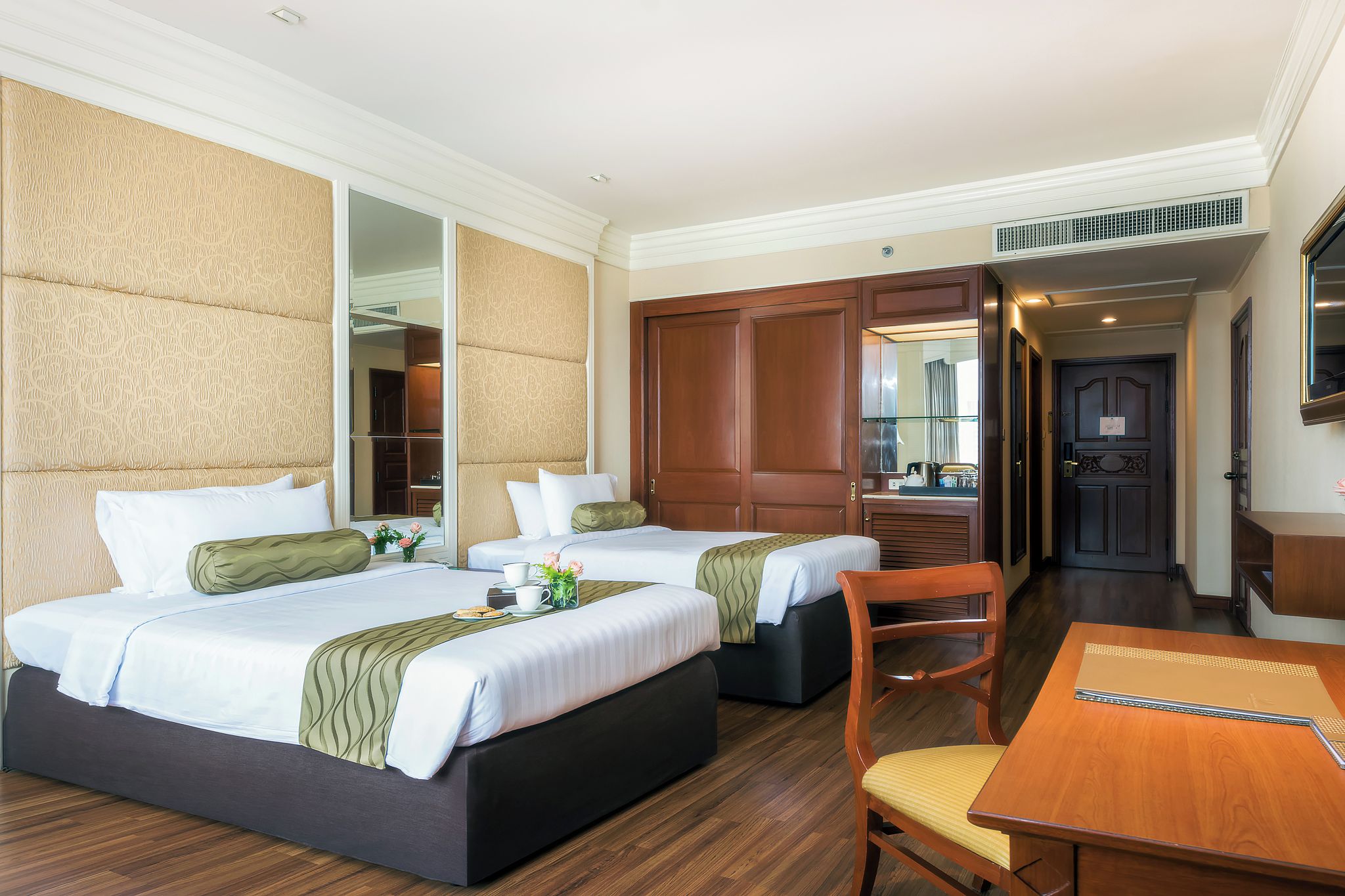 A hotel room with two beds, a wooden dining table, and a chair.