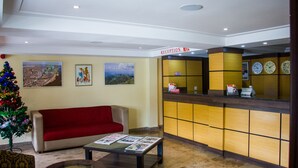 A reception area with a red sofa, a Christmas tree, and framed pictures on the wall. - Sun Heaven Hotel & Resort Lekki (Lekki)