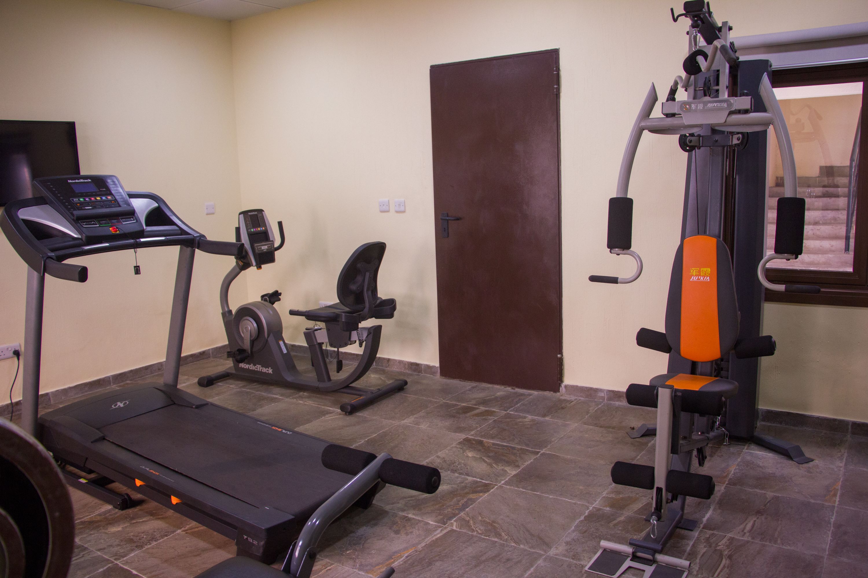 Ein Fitnessstudio mit Laufband, Crosstrainer und Kraftmaschine.
