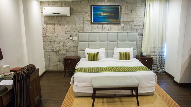 A hotel room with a large bed, a headboard, bedside tables, a desk, and a chair. - Sun Heaven Hotel & Resort Lekki (Lekki)